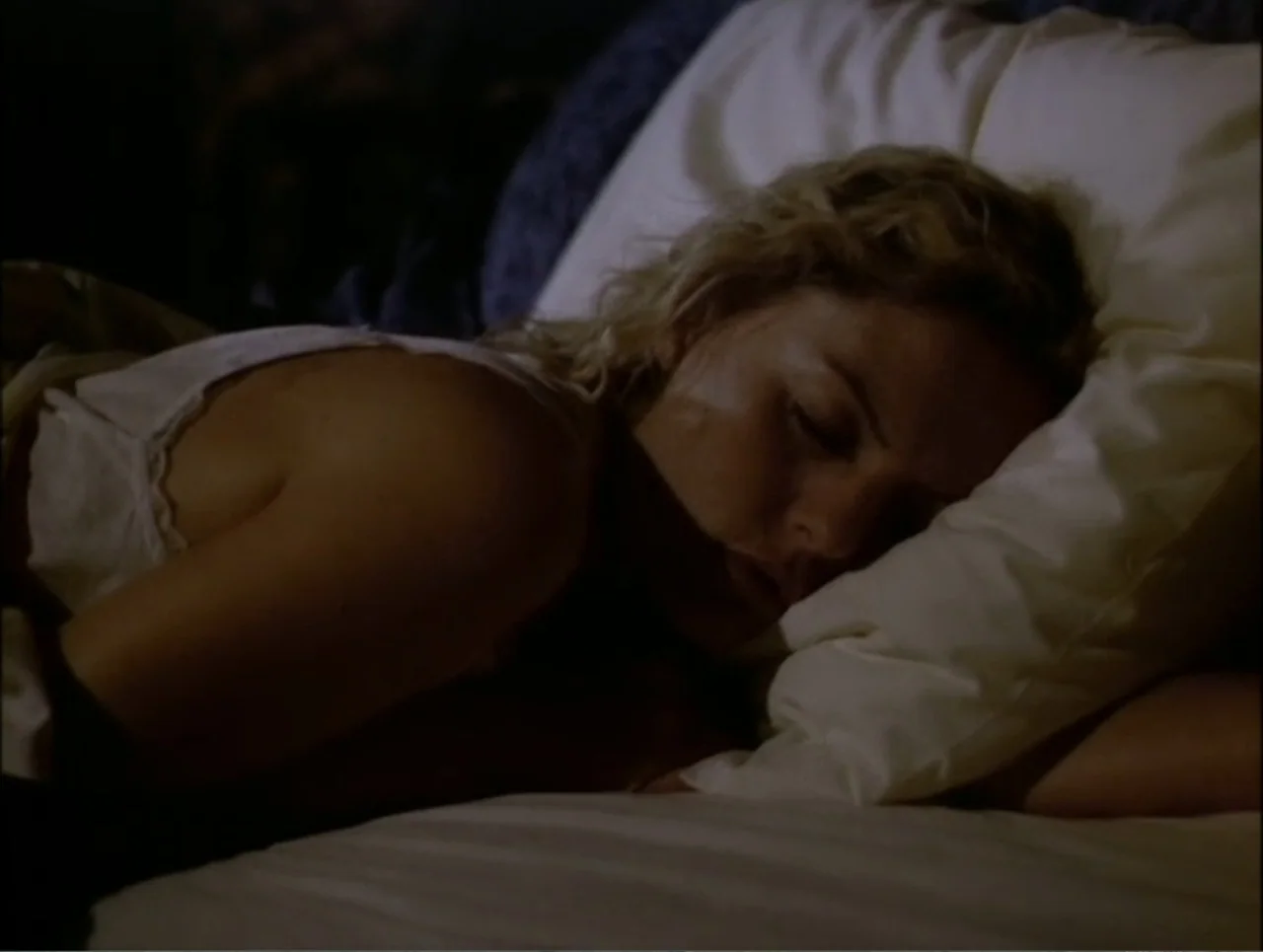 At the Midnight Hour (1995) movie still: closeup — A woman rests on a white pillow inside a dimly lit space. She lies on her side with her eyes…