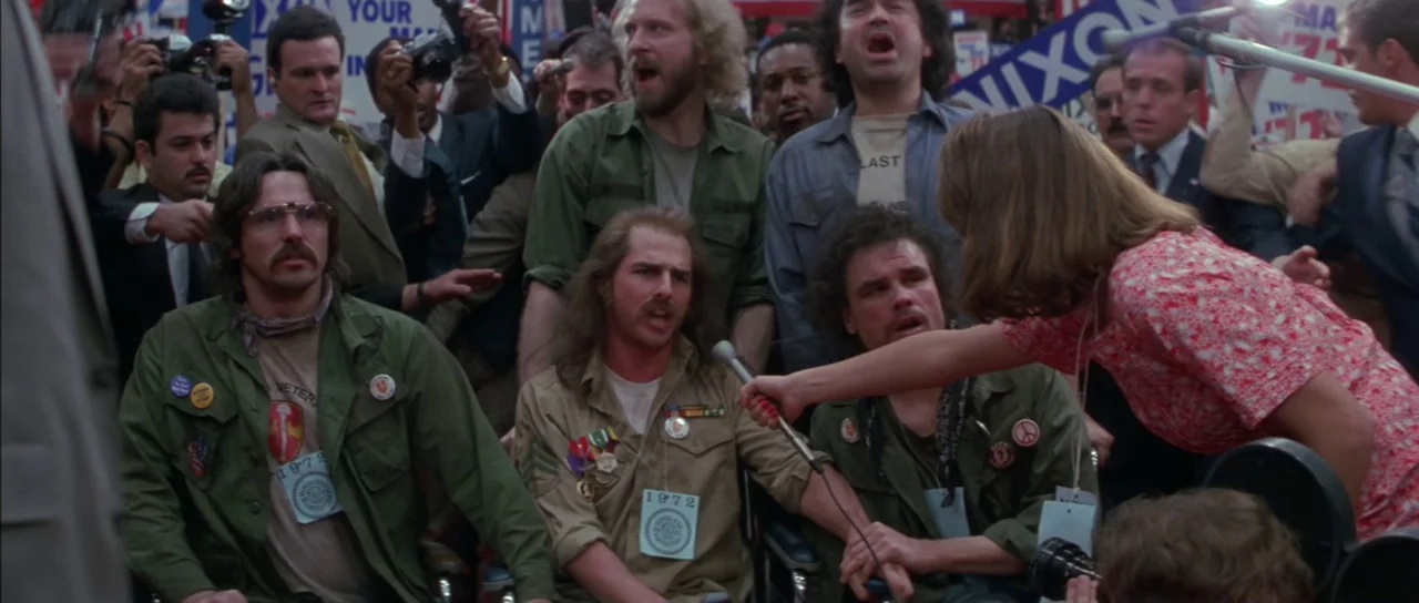 Born On The Fourth of July (1989) movie still: A high-tension moment during a 1972 protest where a group of veterans in wheelchairs are interviewed…