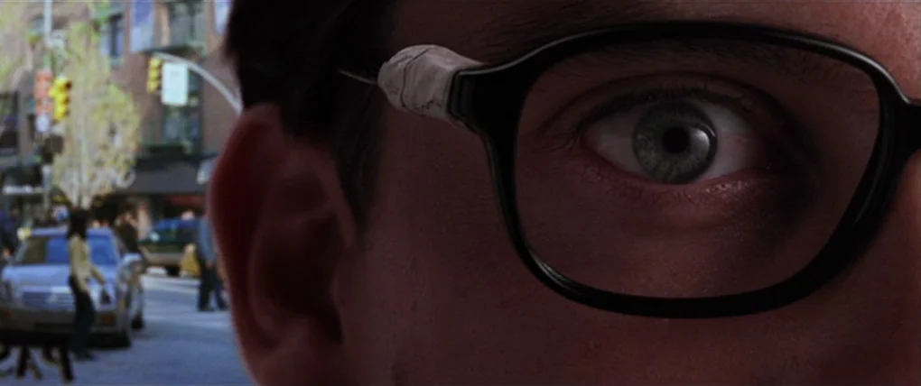 Spider-Man 2 (2004) movie still: An intense, intimate extreme closeup focusing on a character's eye peering through thick glasses. The background is…