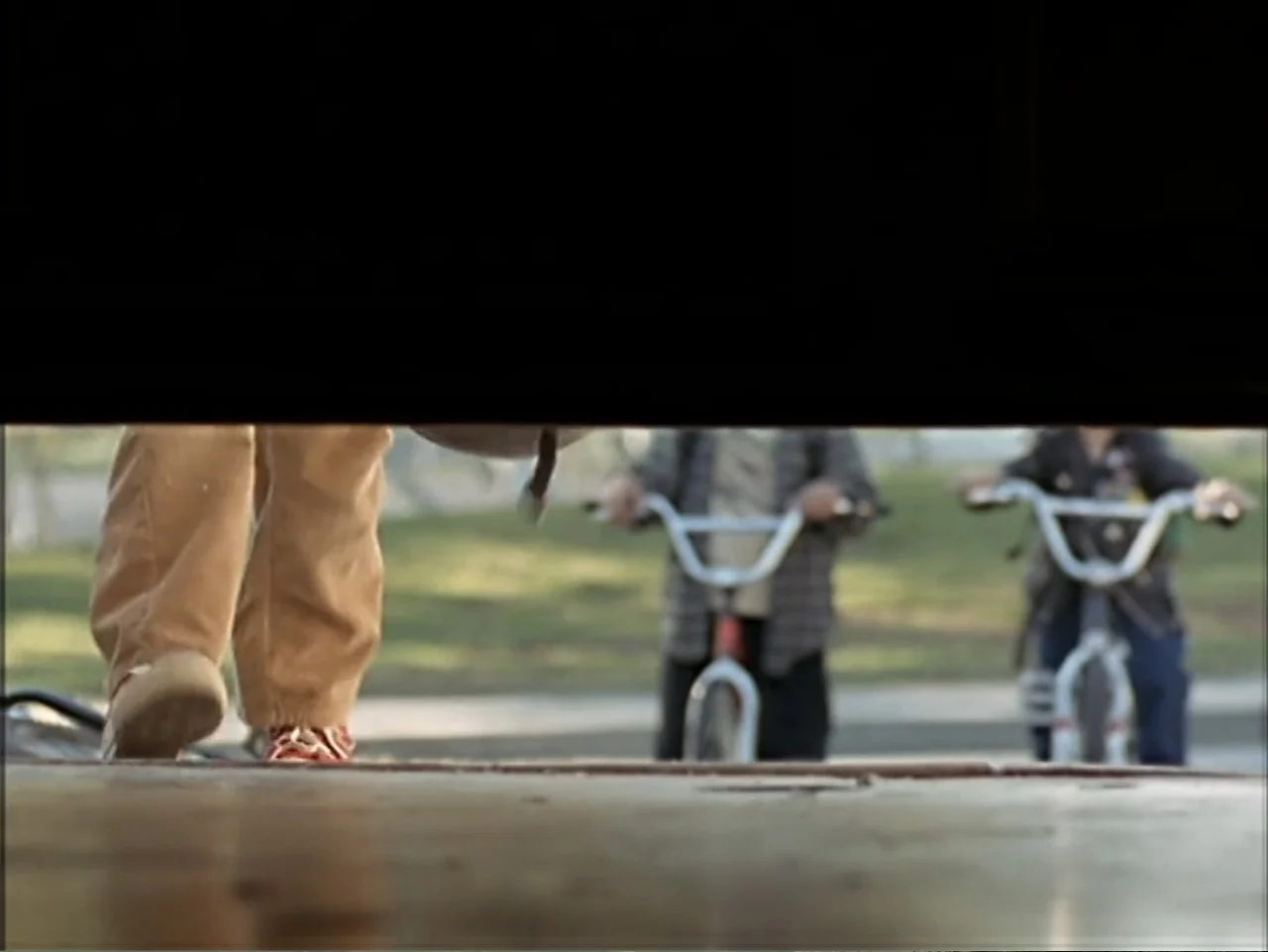 Just 4 Kicks (2003) movie still: medium — A dark garage interior looks out onto a grassy suburban yard in daylight. A child walks out of the garage…