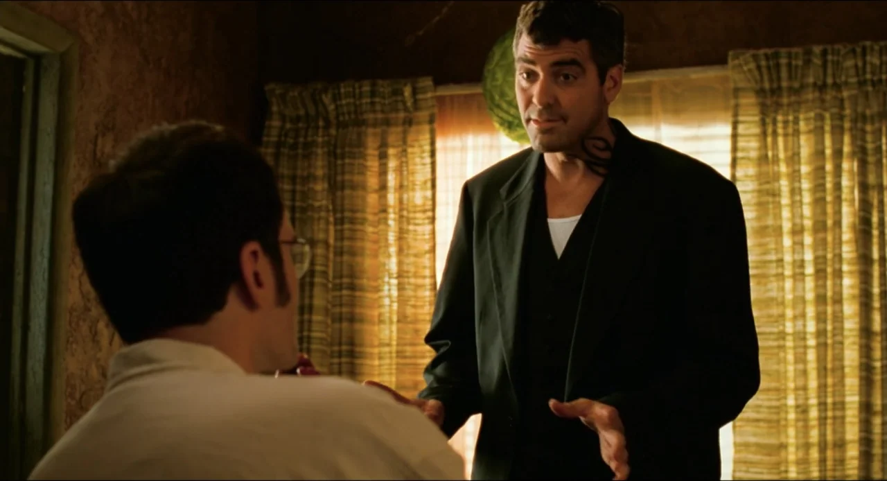 From Dusk Till Dawn (1996) movie still: medium — A dimly lit room with brown textured walls and closed curtains covering the windows. A man with a…