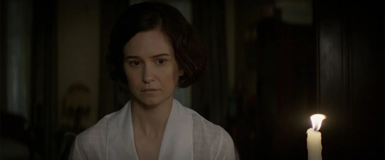 Fantastic Beasts and Where to Find Them (2016) movie still: medium — A dimly lit indoor space features a woman framed against a dark, indistinct…