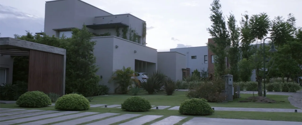I Trust in You (2016) movie still: establishing — Modern minimalist houses are set along a landscaped suburban street with manicured lawns. A…