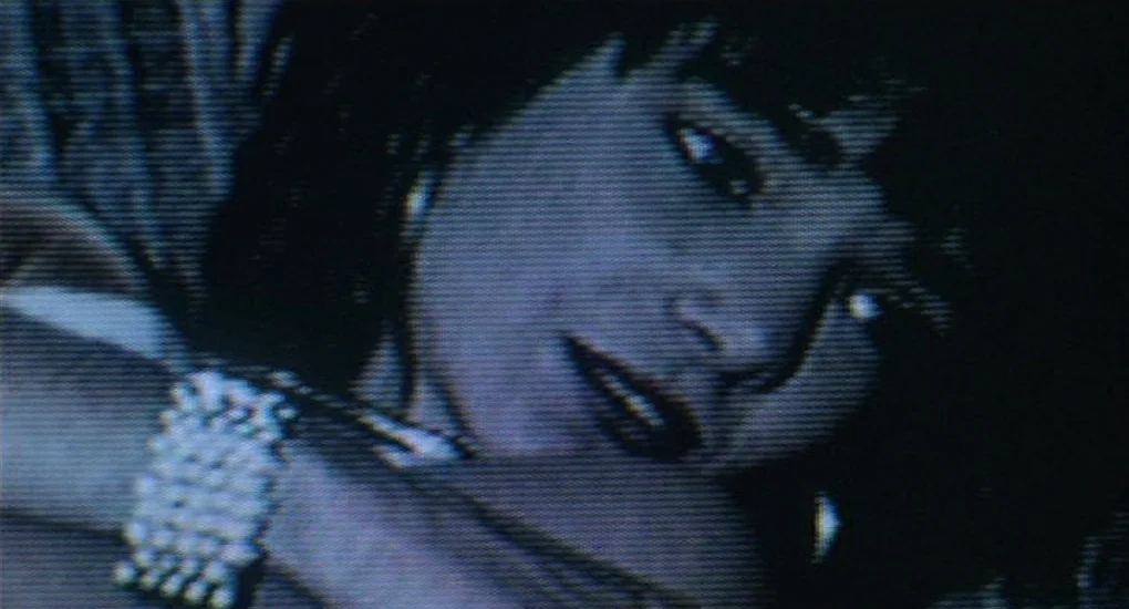 Sex, Lies And Videotape movie still: closeup — A close-up view shows a person resting their face on a hand. The image quality is heavily distorted…