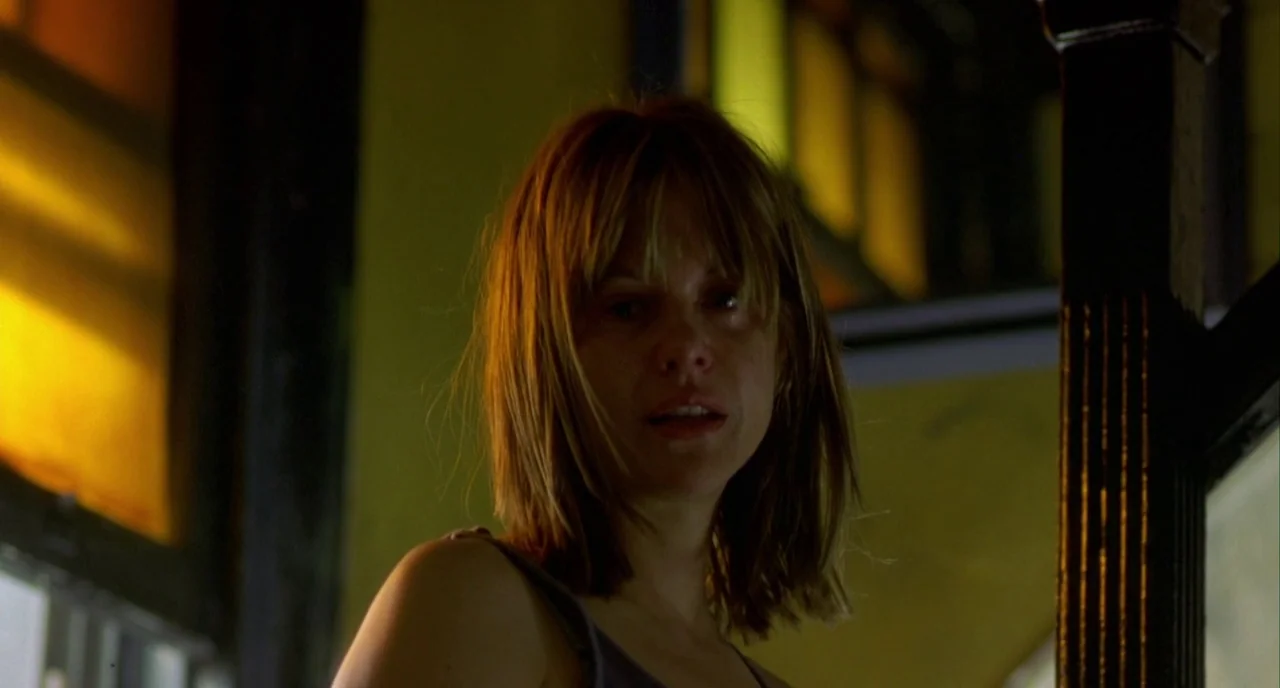 In The Cut (2003) movie still: medium — A stairwell featuring wooden balusters and filtered light through colored glass panes. A woman stands in the…