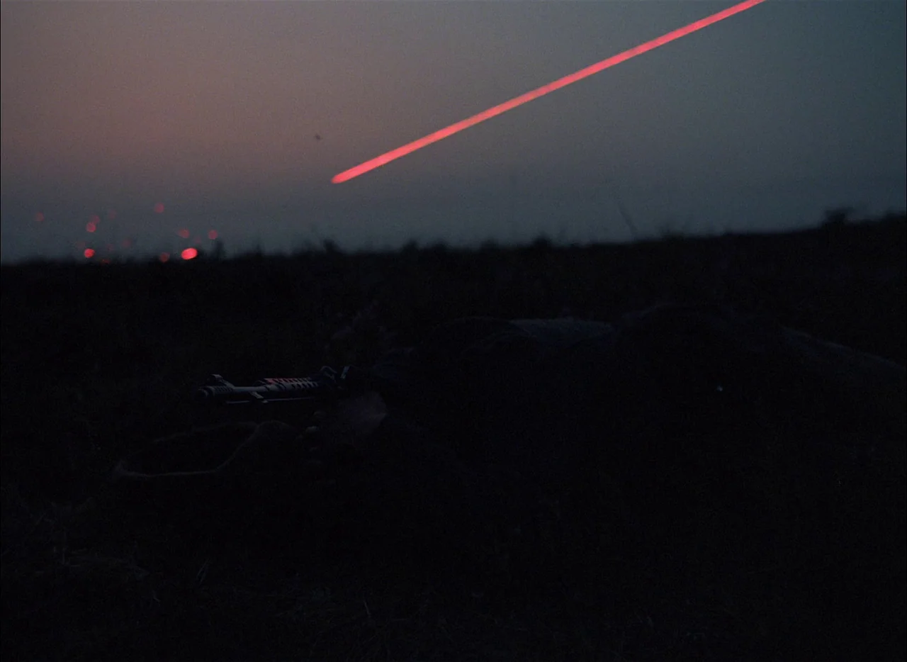 Come and See (1985) movie still: wide — A dark, uneven open field sits under a fading twilight sky at night. A single bright red tracer round…