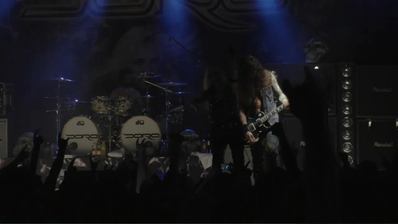 Soaring Highs and Brutal Lows: The Voices of Women in Metal (2015) movie still: medium — A dark concert stage features drum kits and large speaker…