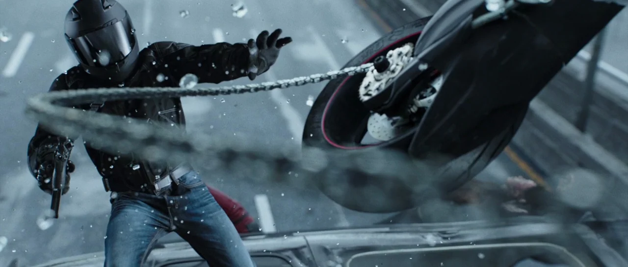 Deadpool (2016) movie still: medium — A motorcyclist stands on a car roof amidst rain droplets on a highway. The subject swings a metallic chain…