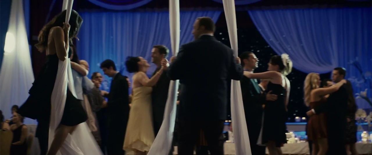 Zookeeper (2011) movie still: fullbody — A dark event space features long white fabric panels hanging from the ceiling. Multiple couples move…
