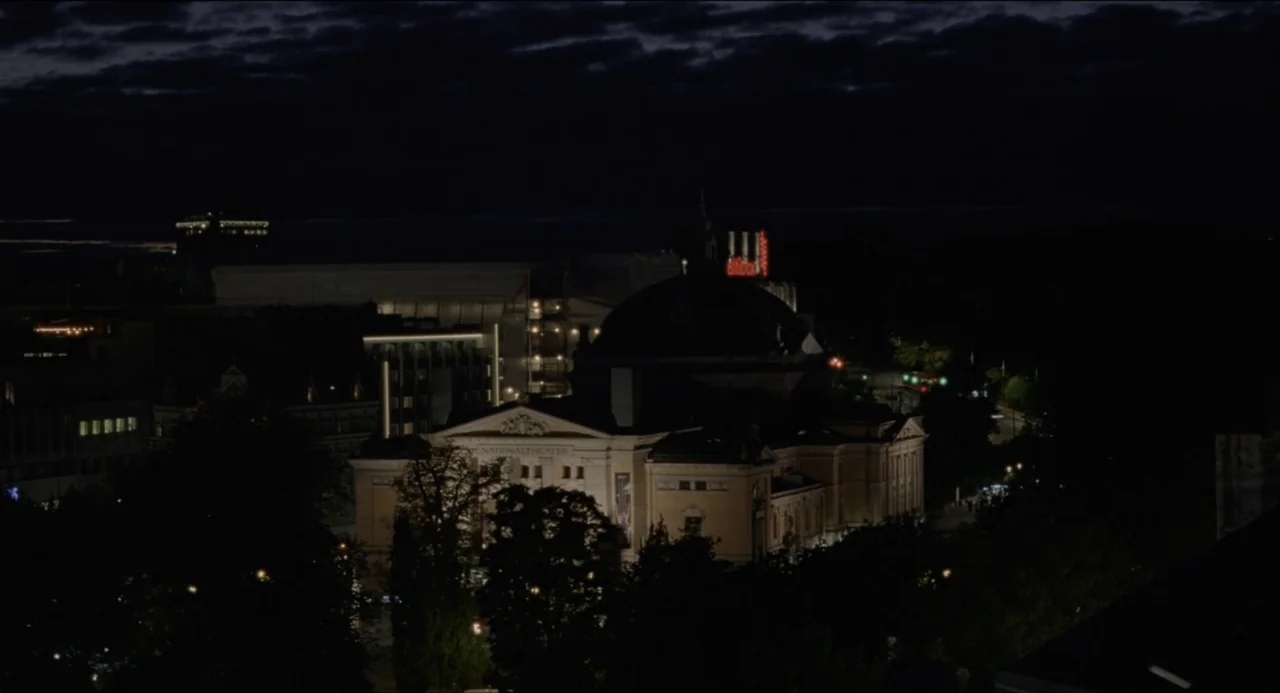 Sentimental Value (2025) movie still: wide — A historic building sits in a dark city park during the night. The facade is illuminated while the…