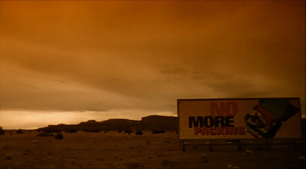 Clockers (1995) movie still: wide — A desolate desert landscape extends under an expansive sky colored by a deep sunset. A large rectangular…