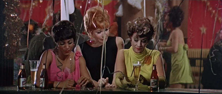 Sweet Charity (1969) movie still: medium — A festive bar interior decorated with streamers and red wall panels. Three women sit together at the…