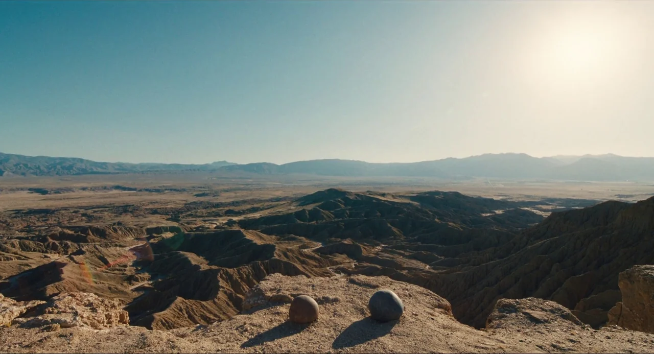 Everything Everywhere All At Once (2022) movie still: establishing — A vast arid desert landscape stretches toward distant mountains under a clear…