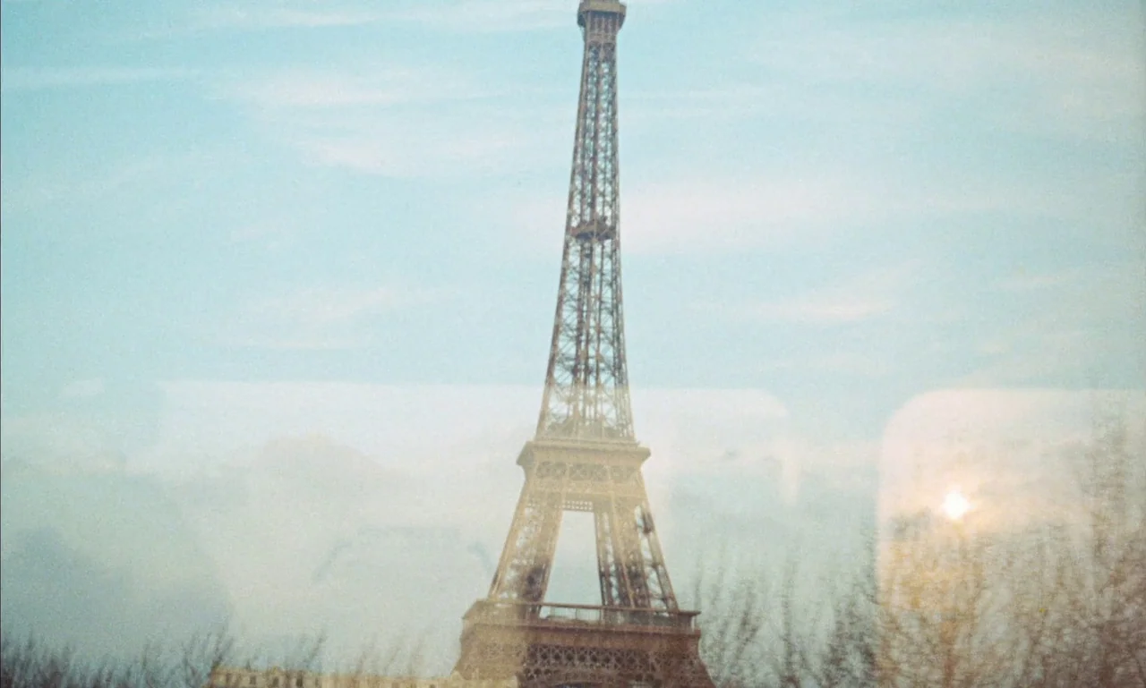 Mandabi (1968) movie still: wide — The Eiffel Tower rises prominently in the center of a hazy, bright daytime frame. The view is partially obscured…