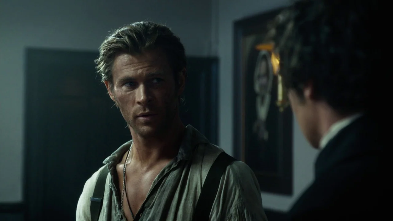 In The Heart of the Sea (2014) movie still: medium — A dark study contains a portrait on the wall and dim interior lighting. A disheveled man looks…