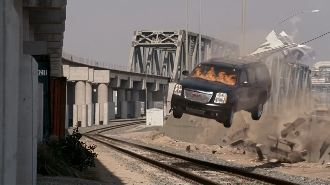 Get Smart (2008) movie still: wide — A desolate railway track runs beside large concrete support pillars and industrial structures. A black SUV…