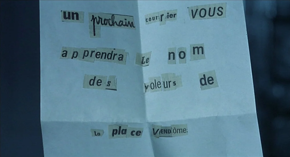 Le Cercle Rouge (1970) movie still: closeup — A folded piece of white paper features ransom-style text created from cut-out magazine clippings. The…
