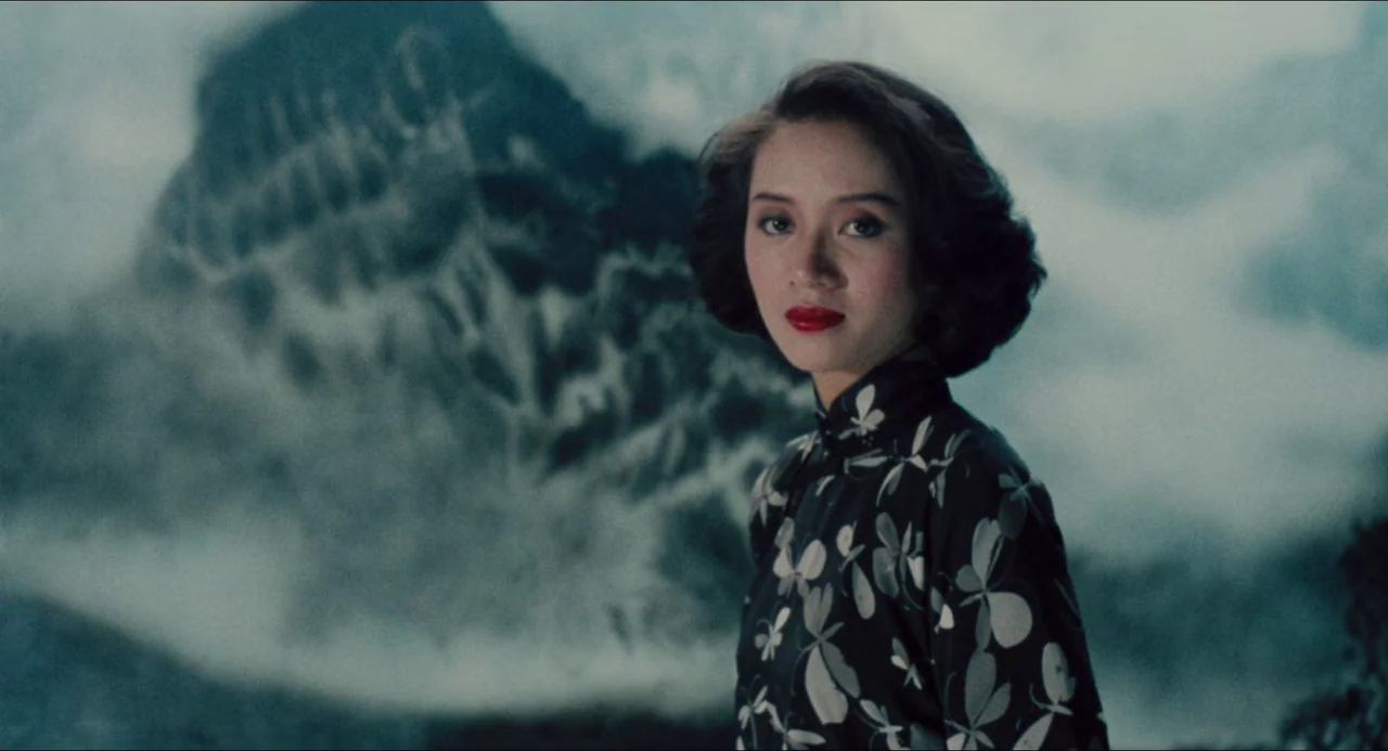 Rouge (1987) movie still: medium — A woman stands in front of a blurred, large rock formation resembling a mountain. She remains motionless while…