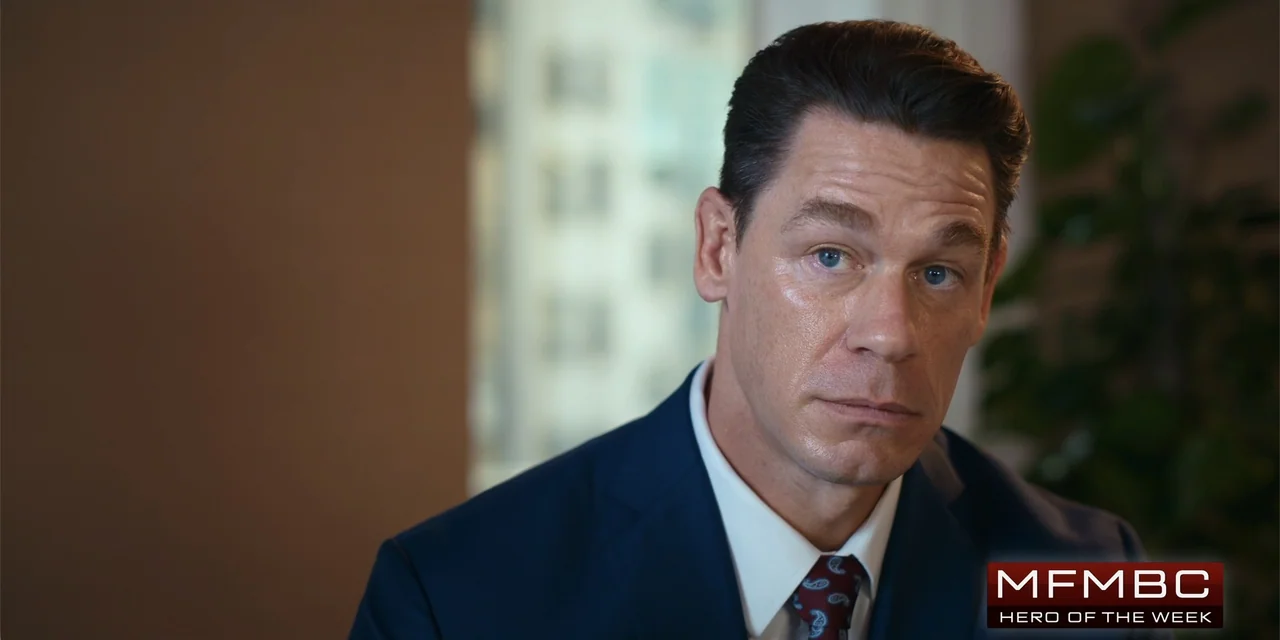 Ricky Stanicky (2024) movie still: closeup — An office interior features a blurred window in the background with indistinct building silhouettes. A…