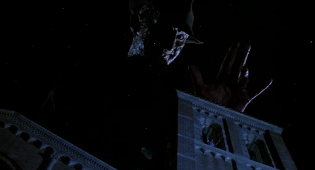 A Nightmare On Elm Street 3: Dream Warriors (1987) movie still: wide — A dark night scene features a colossal scarred figure looming over a stone…