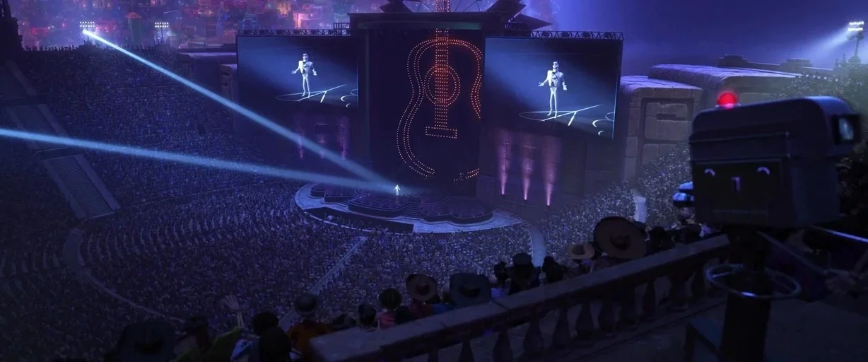 Coco (2017) movie still: wide — A massive open-air stadium at night is filled with a seated audience of skeletons. A performer stands on a central…