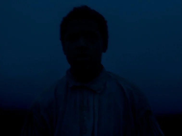 Wuthering Heights movie still: medium — A dark outdoor space at night shows only the faint silhouette of a boy. The subject stands still against a…