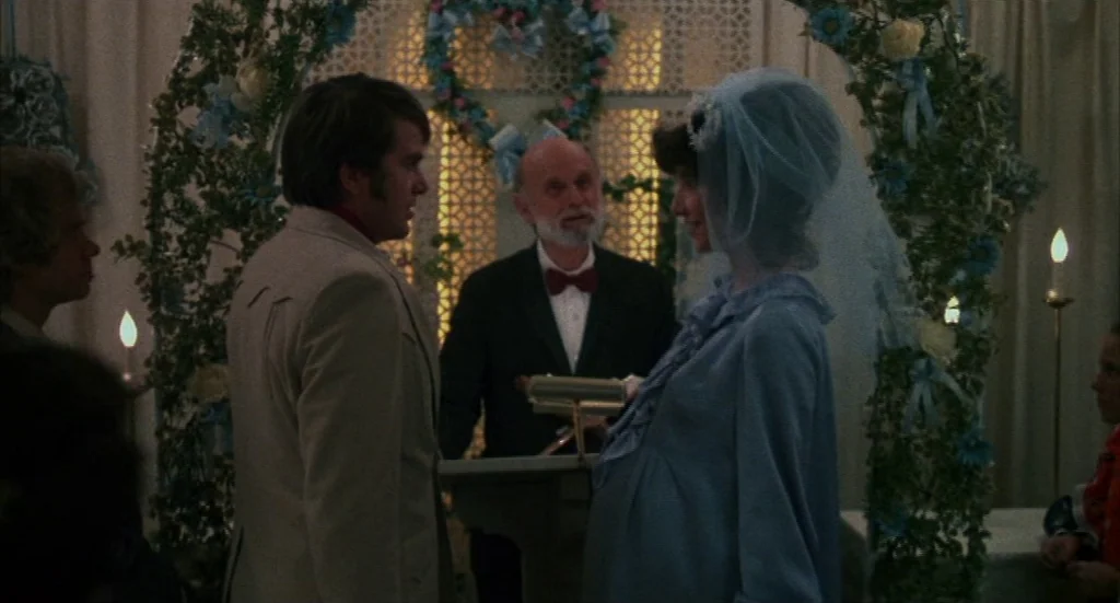 Melvin & Howard (1980) movie still: medium — A wedding ceremony takes place in front of a decorated heart-shaped trellis. An officiant stands at a…