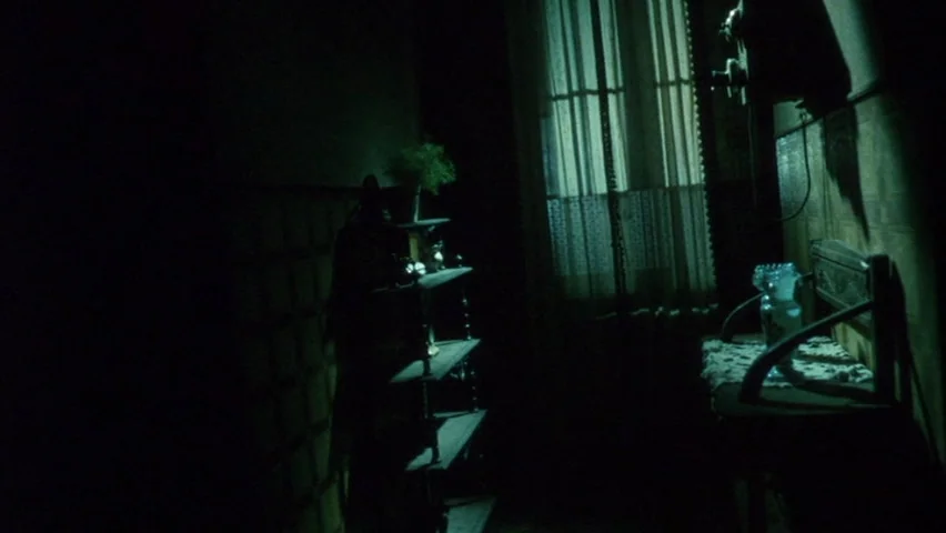Black Sabbath (1963) movie still: wide — A dim room contains a wooden tiered shelf and a bench against a wall. A window with sheer curtains provides…