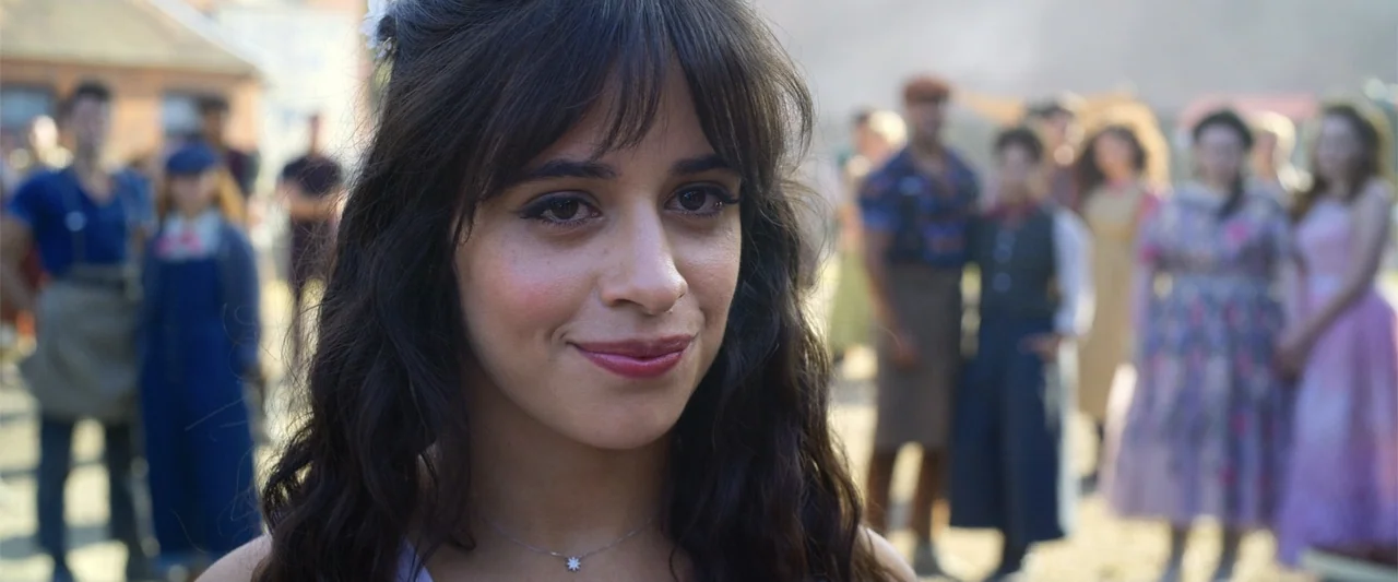 Cinderella (2015) movie still: closeup — An outdoor village square during the day features many people gathered in the background. A woman faces the…