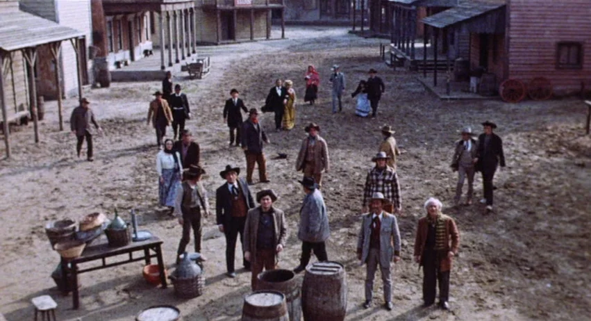 Roy Colt and Winchester Jack (1970) movie still: wide — A dusty town square in the Old West features wooden buildings with covered walkways.…