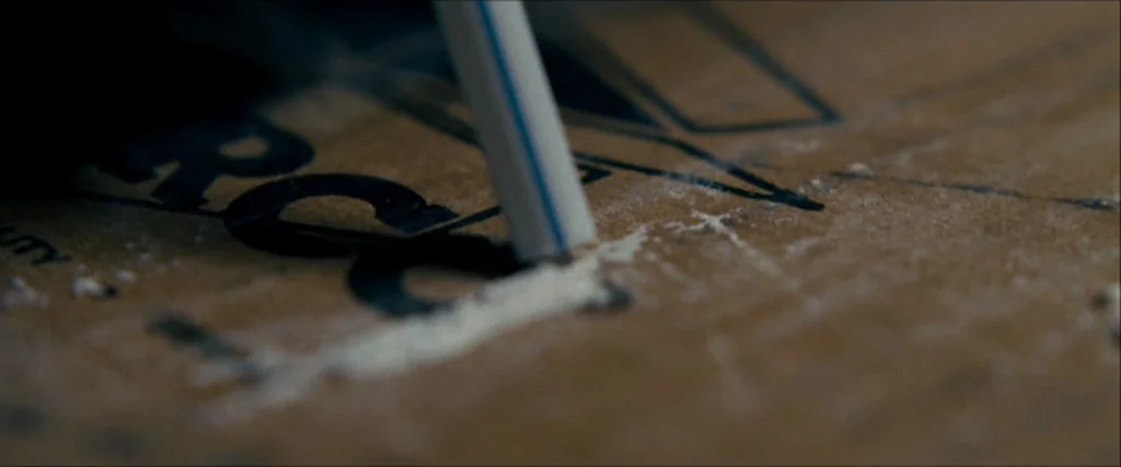 Observe And Report (2009) movie still: closeup — Close up view of a cardboard surface with printed black text and white powder. A single blue and…