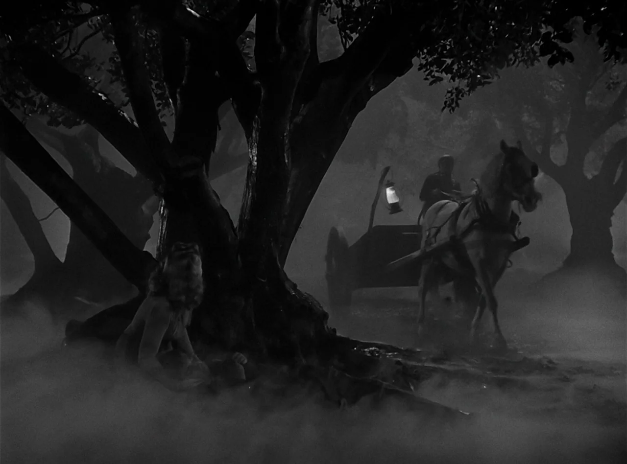 The Wolf Man (1941) movie still: wide — A dark, foggy grove at night with large trees and dense ground-level mist. A horse-drawn cart with a glowing…
