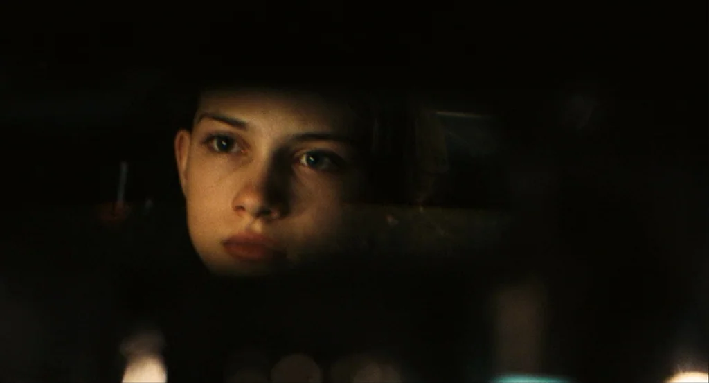 This Night (2008) movie still: closeup — The interior of a vehicle is dark with the driver silhouetted against ambient light. A teenage girl stares…
