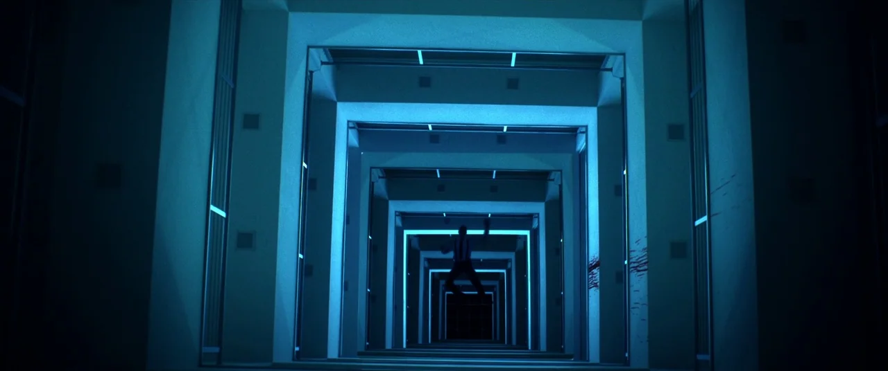 Mayhem (2017) movie still: wide — A long, repeating series of illuminated blue archways creates a symmetrical tunnel structure. A lone male figure…