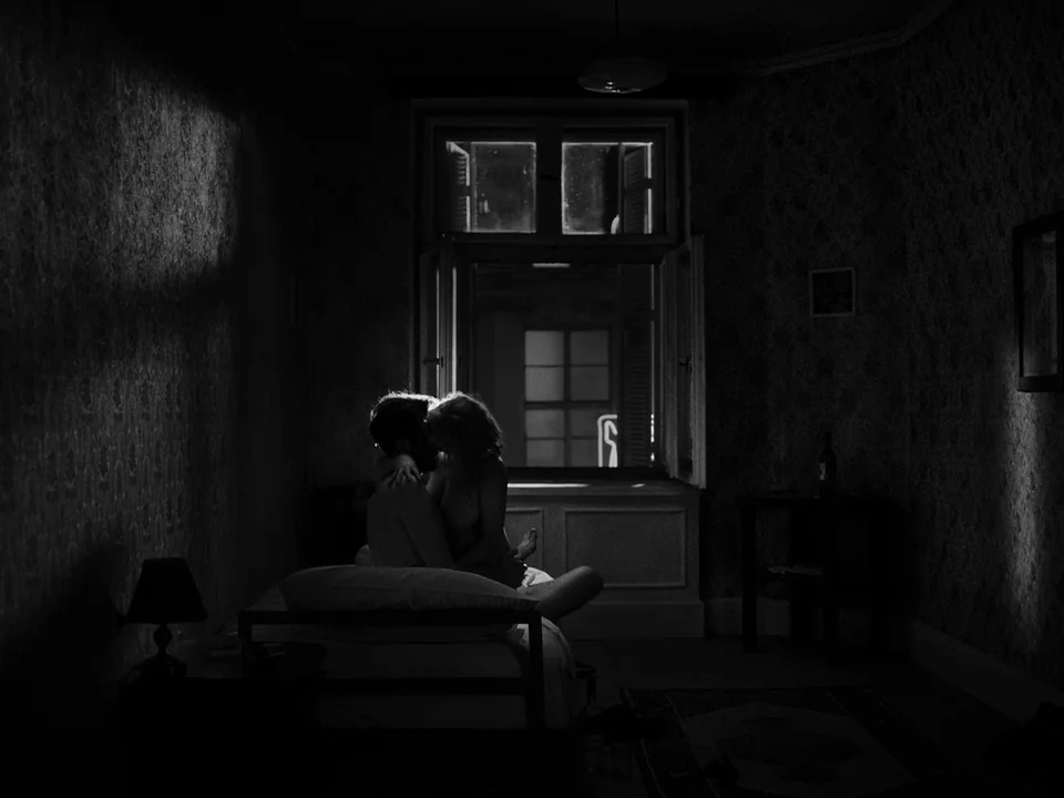 Cold War (2018) movie still: medium — A dark bedroom with patterned wallpaper is illuminated by light from an open window. A man and a woman are…