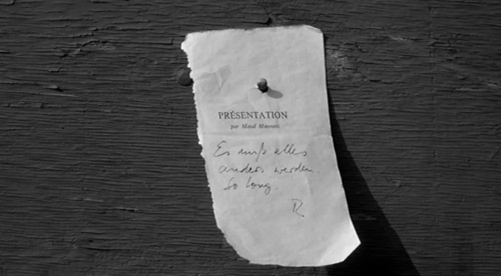 Kings of the Road (Im Lauf der Zeit) (1976) movie still: closeup — A small, ripped piece of paper is pinned to a dark, textured wooden board. The…
