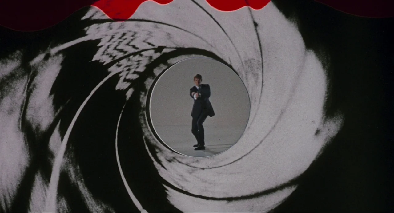 Live and Let Die (1973) movie still: wide — A man stands within the circular aperture of a graphic gun barrel animation. He moves forward through…