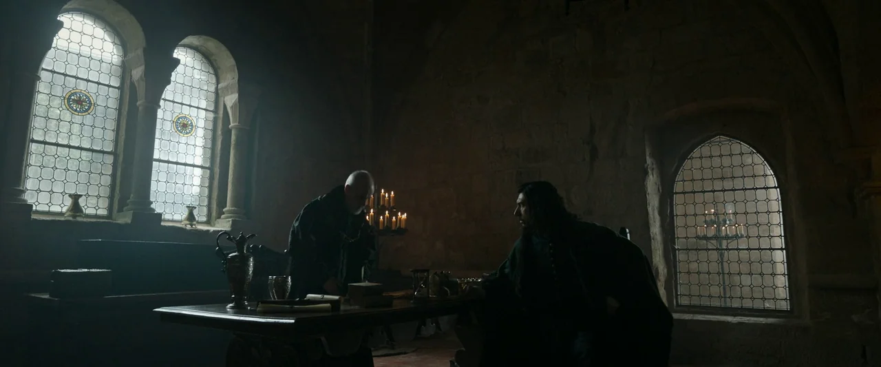 The Last Duel (2021) movie still: wide — A medieval stone room features vaulted ceilings, narrow arched windows, and rough textured walls. Two men…