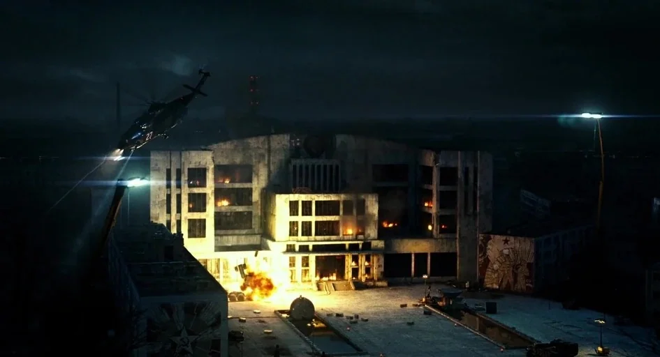 A Good Day to Die Hard (2013) movie still: wide — A brutalist concrete building with a Soviet-style mural sits at night under fire. An explosion…
