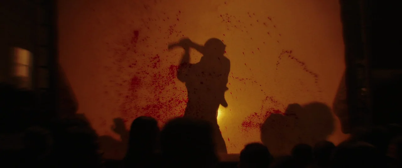 Impetigore (2019) movie still: medium — A silhouette is projected onto a bright orange screen covered in blood splatters. The audience remains as…