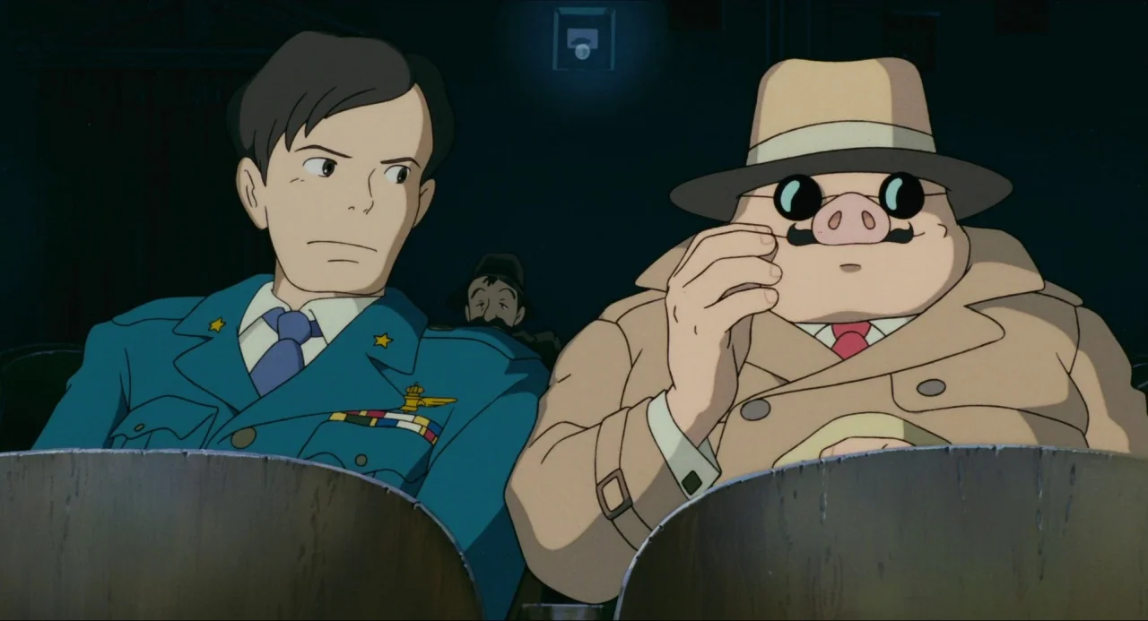 Porco Rosso (1992) movie still: medium — Two men sit side by side in the dark auditorium of a vintage cinema. One wears a blue pilot-style uniform…