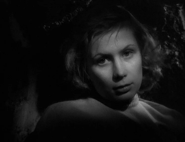 Prison (1949) movie still: closeup — A dark space provides a stark background for a young woman's face. The subject is positioned slightly…