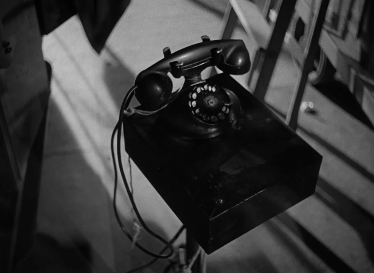 The Bad and the Beautiful (1952) movie still: closeup — A black rotary telephone rests on a rectangular wooden box in a studio space. The frame…
