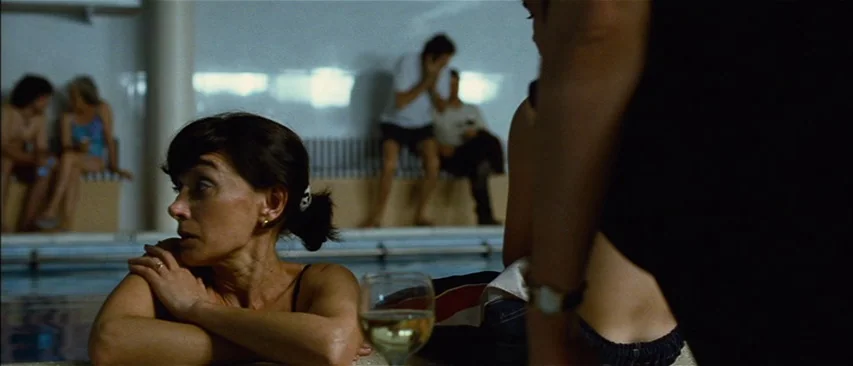 The Headless Woman (2008) movie still: medium — An indoor swimming pool with a tiled wall and a person in the foreground. A woman rests her arms on…