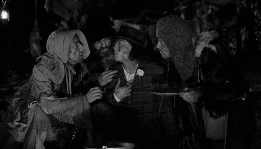 Dead Man (1995) movie still: medium — A group of people dressed in period clothing gather at a night campsite. The figures lean inward toward each…
