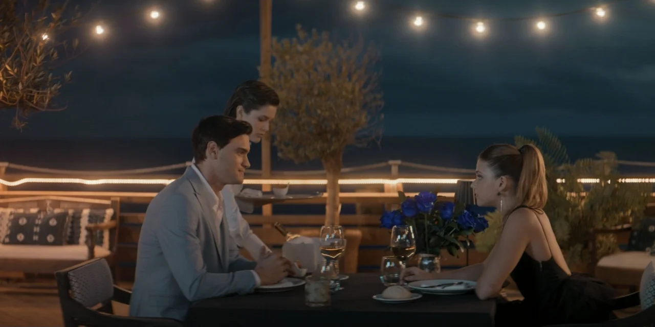 Your Fault (2024) movie still: medium — An outdoor restaurant dining area at night features tables under glowing string lights. A young man and…