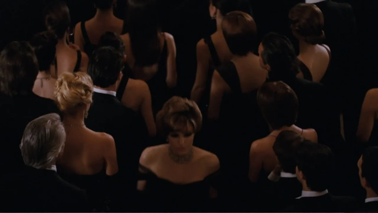 The Tourist (2010) movie still: medium — A crowded interior space filled with people dressed in formal black evening wear. The subjects stand…