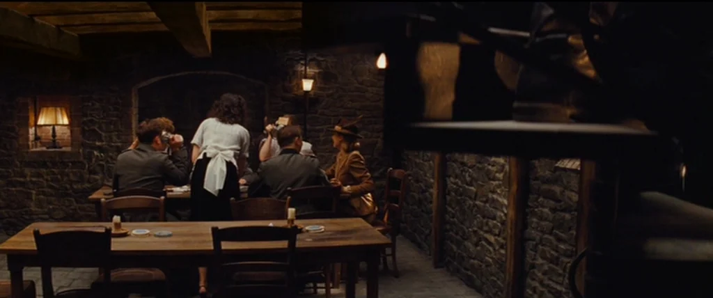 Inglourious Basterds (2009) movie still: wide — A dimly lit 1940s tavern features rugged stone walls and wooden furniture. A small group of people…