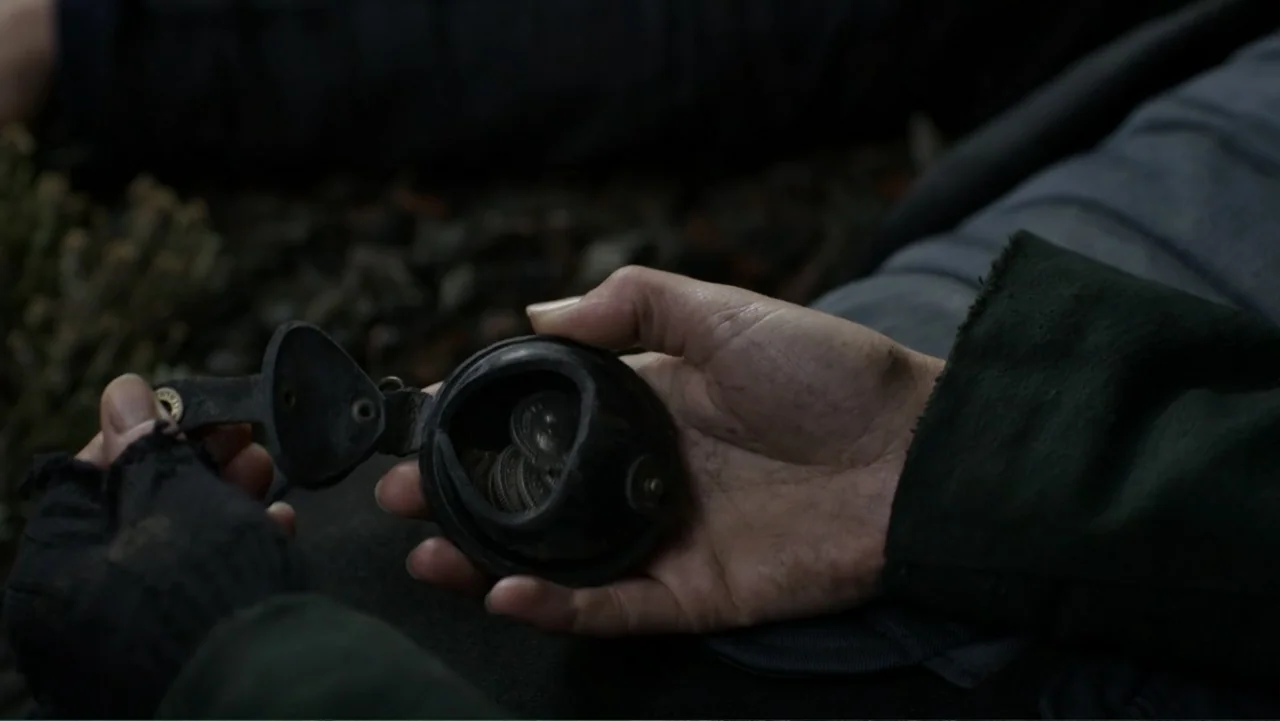 Mortal Engines (2018) movie still: closeup — An open leather coin pouch rests in a person's palm against an earthy background. The fingers of…