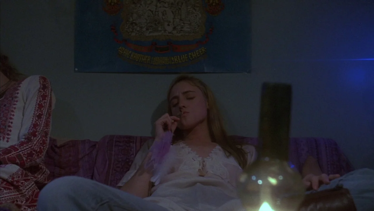 Baby It’s You (1983) movie still: medium — A dark living room with a Big Brother and the Holding Company band poster. A young woman with long blonde…